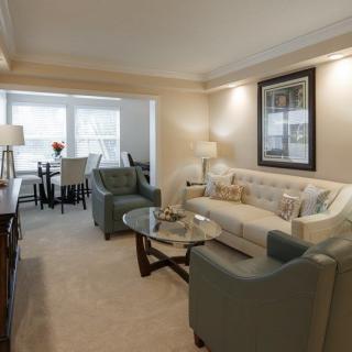 A cozy living room with a comfortable sofa, armchairs, and a dining area in the background.