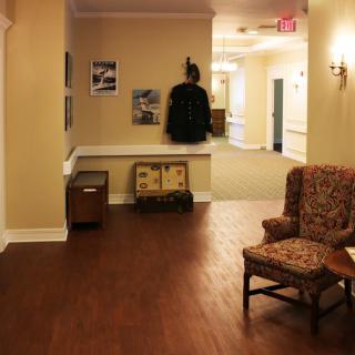 A cozy hallway with a patterned chair, a coat rack, and wall decorations.