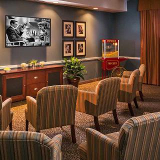 A cozy home theater setup with striped chairs, a mounted TV, and a popcorn machine.