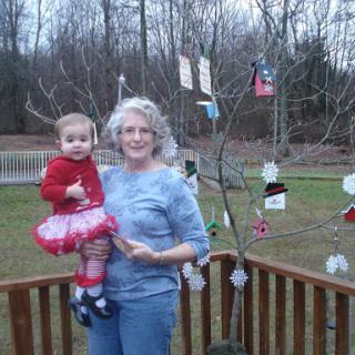 A joyful moment shared between a child and an adult, surrounded by festive decorations on a tree.