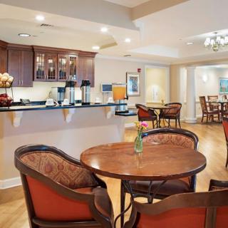 A cozy lounge area with wooden tables and chairs, featuring warm lighting and elegant decor.