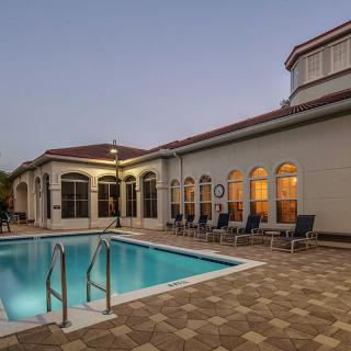A serene evening view of a swimming pool next to a beautifully lit building.