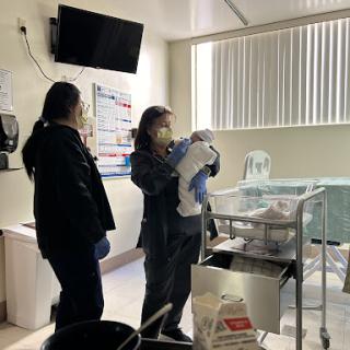 Healthcare professionals caring for a newborn in a hospital setting.