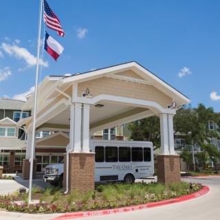 A building with a covered entrance featuring two flags and a parked vehicle, set against a clear blue sky.