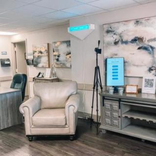 A well-furnished office waiting area with a comfortable chair, artwork on the walls, and a reception desk.