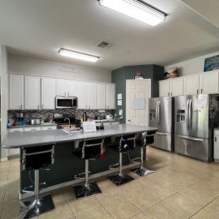 A modern kitchen featuring a spacious island with bar stools, stainless steel appliances, and white cabinetry.