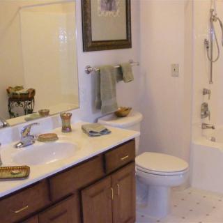 A well-organized bathroom with a sink, mirror, toilet, and bathtub.
