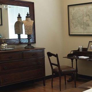 A vintage-style office with a wooden dresser, mirror, and desk.
