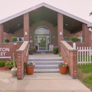 A welcoming entrance to a community building, showcasing brick architecture and beautiful landscaping.