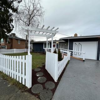 A suburban house with a white fence and pergola in the front yard.