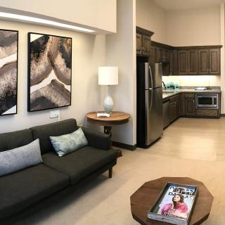 A modern open-plan living room with a sofa, coffee table, and integrated kitchen.