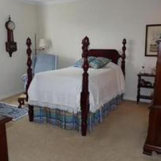 A cozy bedroom featuring a four-poster bed with traditional wooden furniture.