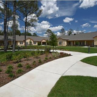 A scenic view of a modern residential building with a curved pathway and landscaped garden under a partly cloudy sky.