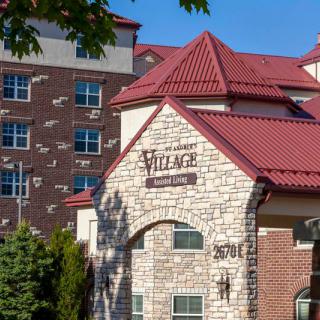 A modern apartment complex with a stone facade and red roof under a clear blue sky.