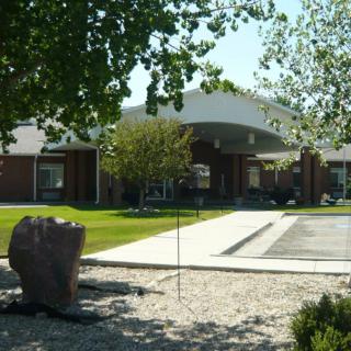 A view of a building with an entrance surrounded by trees and landscaping.