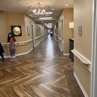 A long, well-lit hallway with chandeliers and patterned flooring.