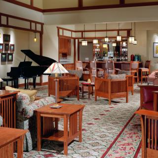 A spacious living room with a modern decor featuring wooden furniture and a grand piano.