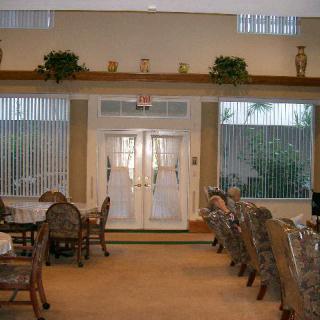 An elegant dining area with neatly arranged tables and chairs leading to glass doors, adorned with plants.