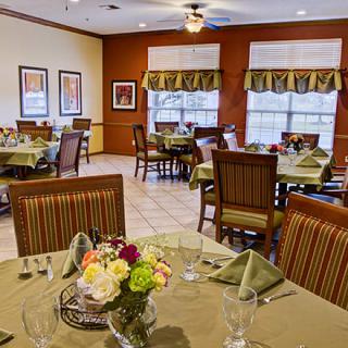 A warmly decorated dining room featuring elegant table settings and floral centerpieces.