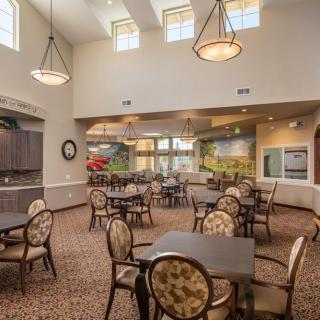 A well-lit dining area with multiple tables and chairs, featuring elegant lighting and decor.