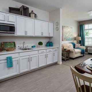 A modern open floor plan featuring a kitchen with white cabinets and an adjacent living area.