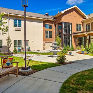 A modern residential building with a landscaped garden and fountain.