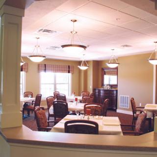 A well-lit dining area featuring multiple tables and chairs, designed for a comfortable dining experience.