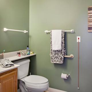 A neatly arranged bathroom with green walls, featuring a toilet, sink, and towel rack.