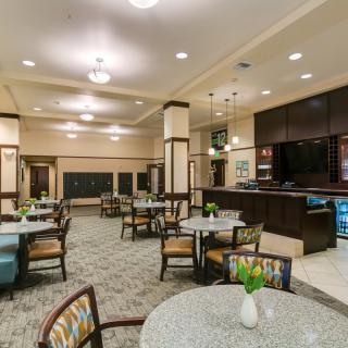A spacious dining area with tables and chairs, featuring a bar counter and elegant lighting.