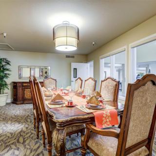 A well-appointed dining room featuring a long wooden table set for a meal, surrounded by ornate chairs and illuminated by a modern chandelier.