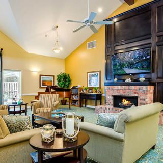 A cozy living room featuring a fireplace, comfortable seating, and a grand piano.