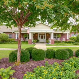A well-landscaped building entrance surrounded by trees and bushes.