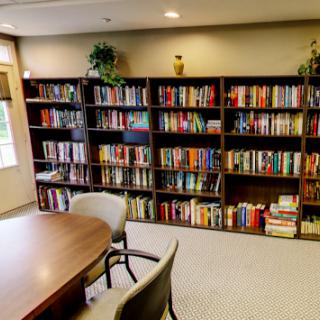 A cozy library space featuring neatly organized bookshelves filled with various books and a small reading area.