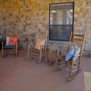 A cozy patio with wooden rocking chairs and colorful cushions against a stone wall.