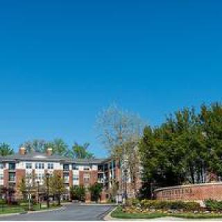 A residential apartment complex surrounded by trees under a clear blue sky.
