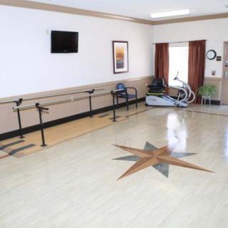 A rehabilitation room with exercise equipment and parallel bars, designed for physical therapy.