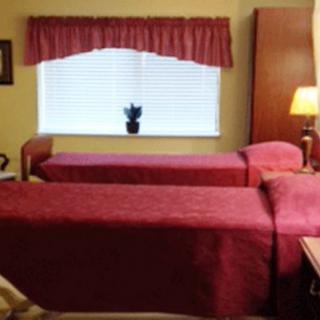 A cozy bedroom featuring two twin beds with red bedding and a window adorned with matching curtains.
