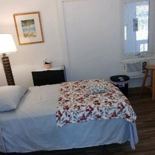 A cozy bedroom with a neatly made bed, bedside lamp, and simple decor.