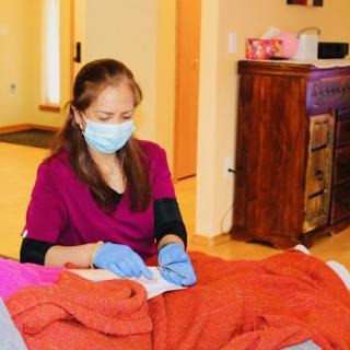 A healthcare professional provides care to a patient in a warm home environment.