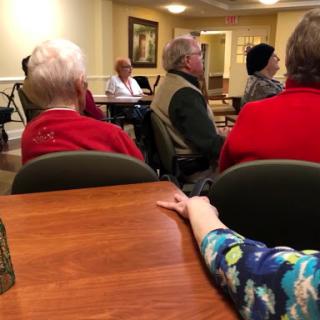 A gathering of seniors engaging in a discussion during a community meeting.