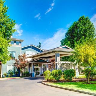 A picturesque building entrance surrounded by lush greenery and a clear blue sky.