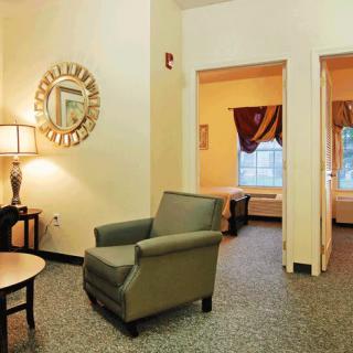 A cozy hotel room with an armchair, table, and decorative mirror.
