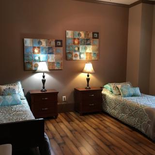 A cozy bedroom with twin beds, bedside lamps, and decorative artwork on the walls.
