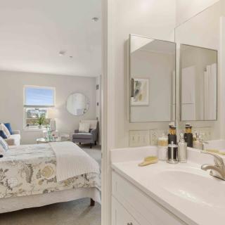 A modern bedroom with an adjacent bathroom, featuring elegant decor and ample natural light.