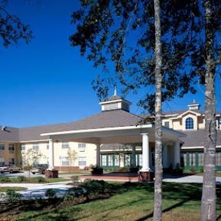 A welcoming hotel entrance surrounded by trees under a clear blue sky.