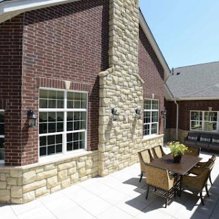 A beautifully designed exterior of a residential building featuring a mix of brick and stone materials, with an inviting outdoor seating area.