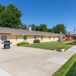 A single-story house with a neatly maintained lawn and driveway, featuring an outdoor grill.