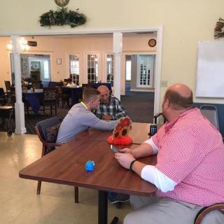 A group of people having a conversation in a casual indoor setting around a table.
