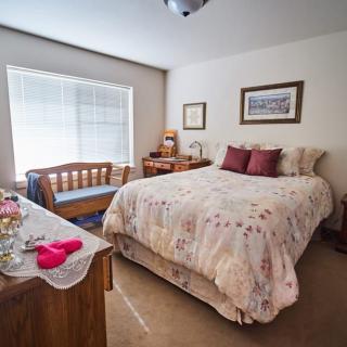 A cozy bedroom with a large bed, wooden furniture, and soft lighting.