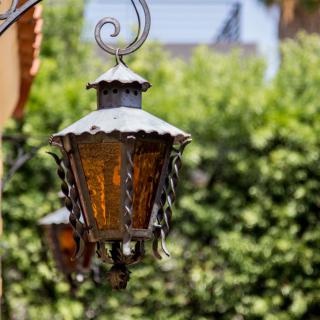 A vintage metal lantern hangs in a garden setting.
